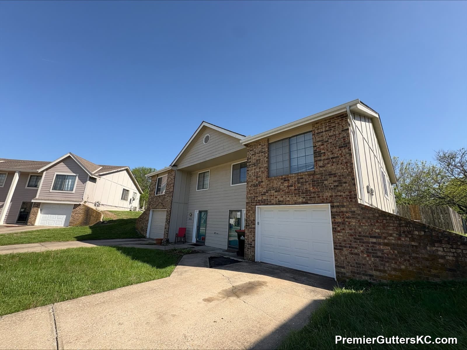 1990s tri-level brick and cream home with new seamless gutters and downspouts in Kansas City