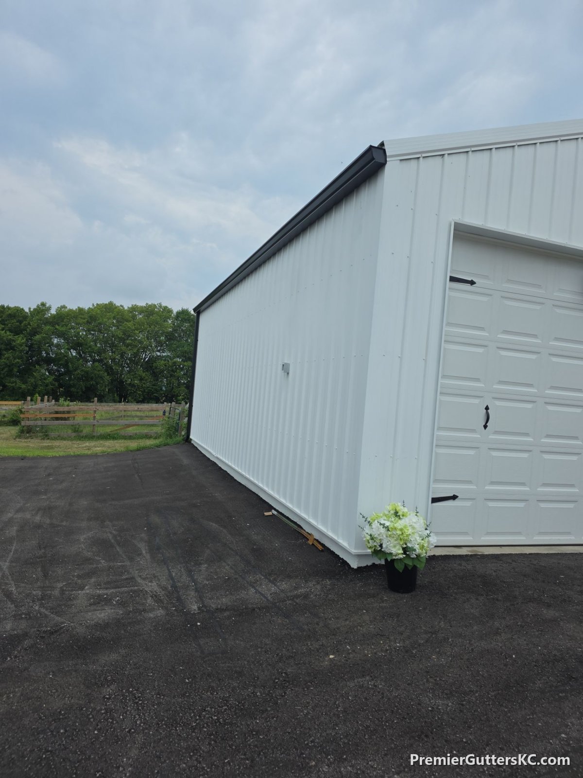 Black gutters installed on a white metal pole barn in Napoleon, Missouri