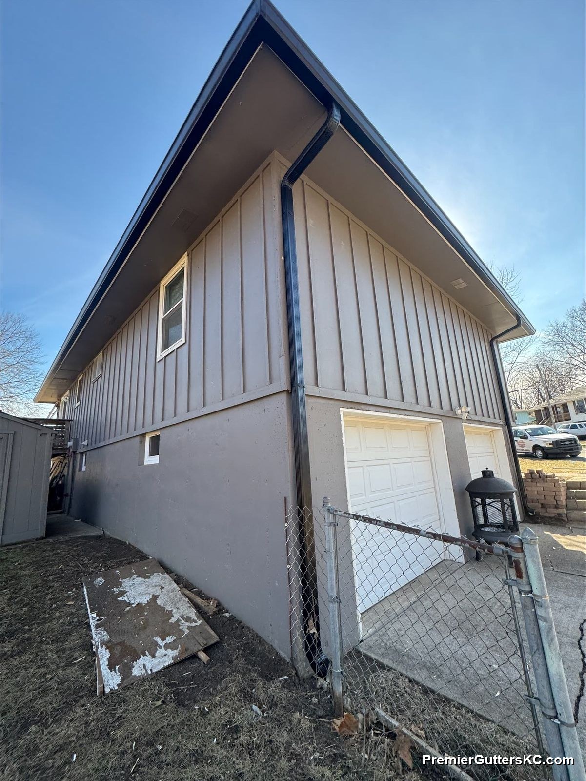 Black seamless gutters on board-and-batten split-level home in Kansas City