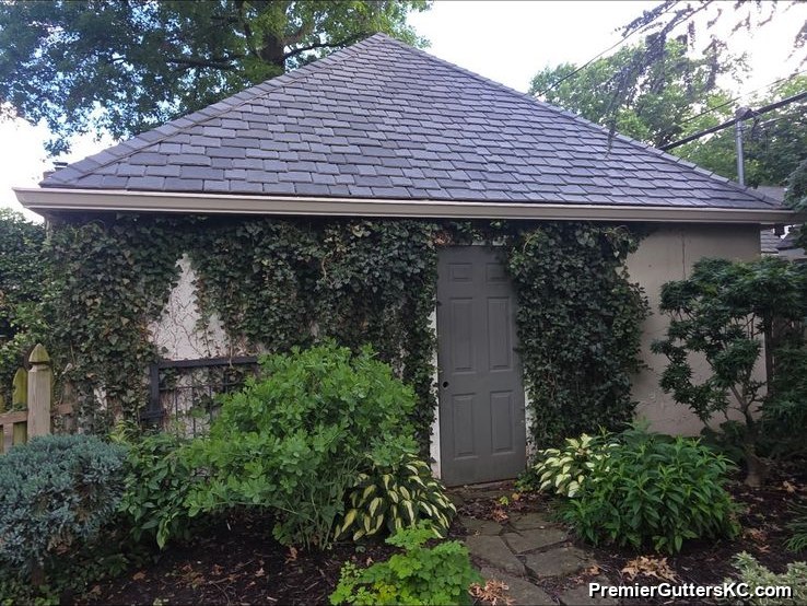 Brick ranch home with a hip roof and seamless gutters nestled behind a lush landscaped garden in the Kansas City metro