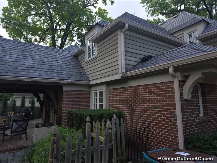 Brick ranch home with a covered pergola patio and white seamless gutters along the eaves, surrounded by mature landscaping in the Kansas City metro