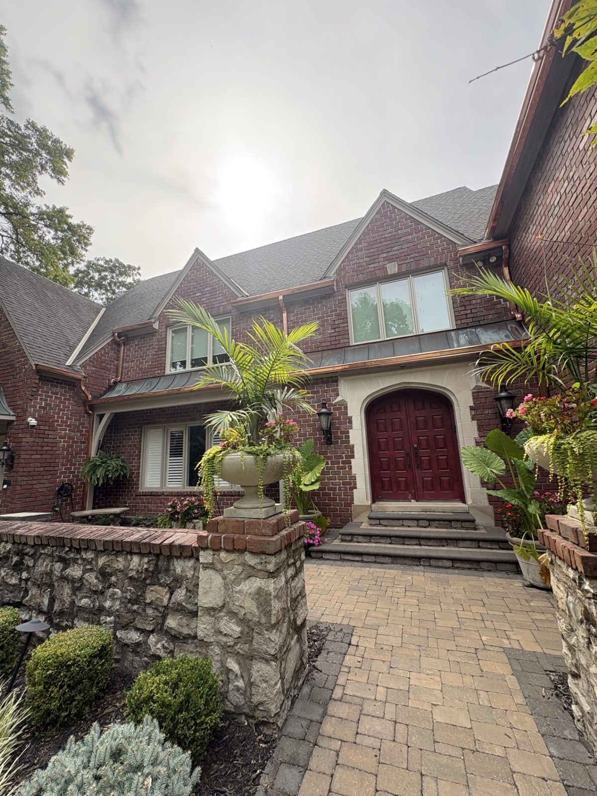 New copper gutters above the arched entry of a brick Tudor home in the Kansas City metro