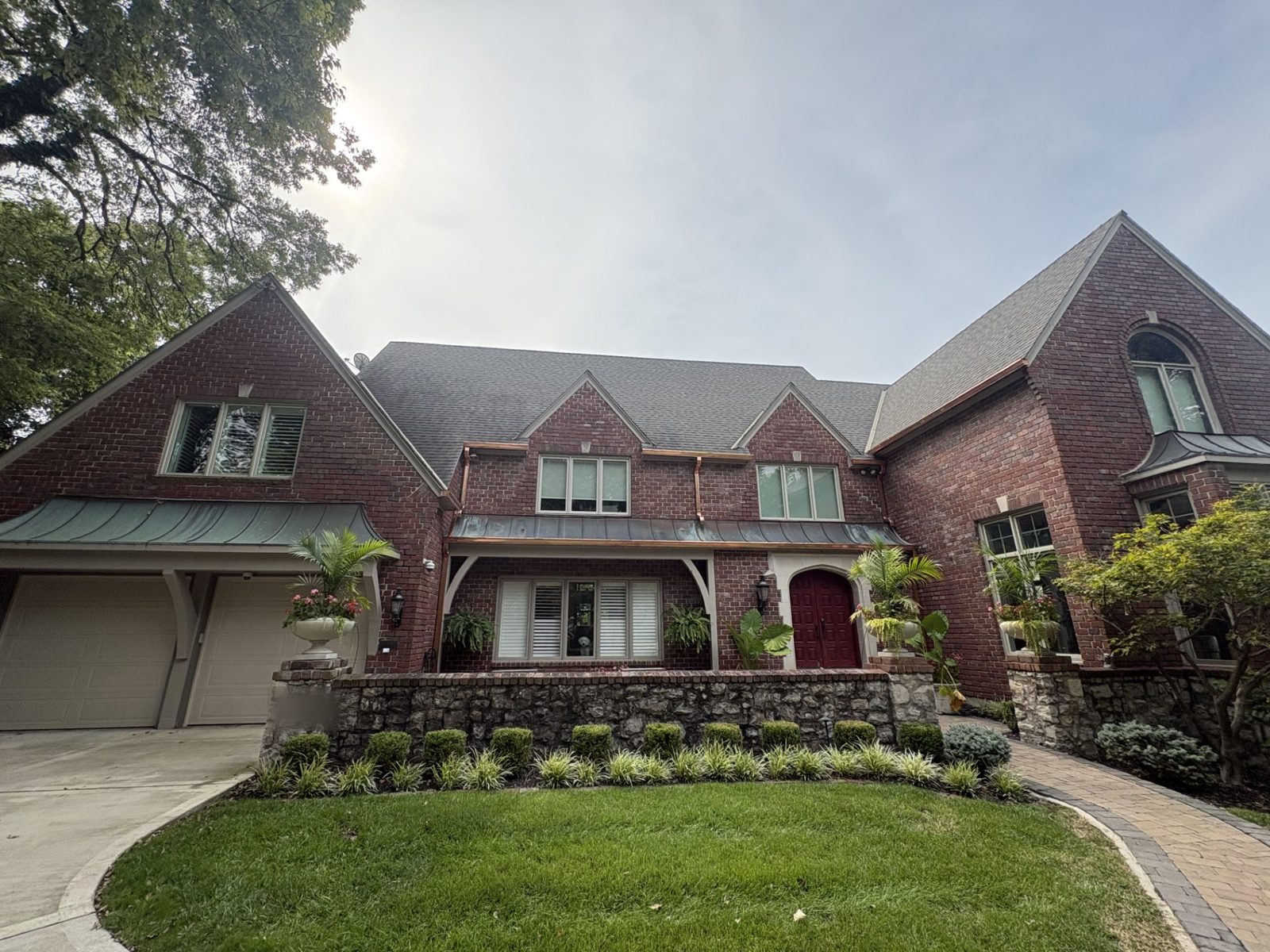 Brick Tudor-style home in the Kansas City metro with new copper gutters and copper downspouts across the front elevation
