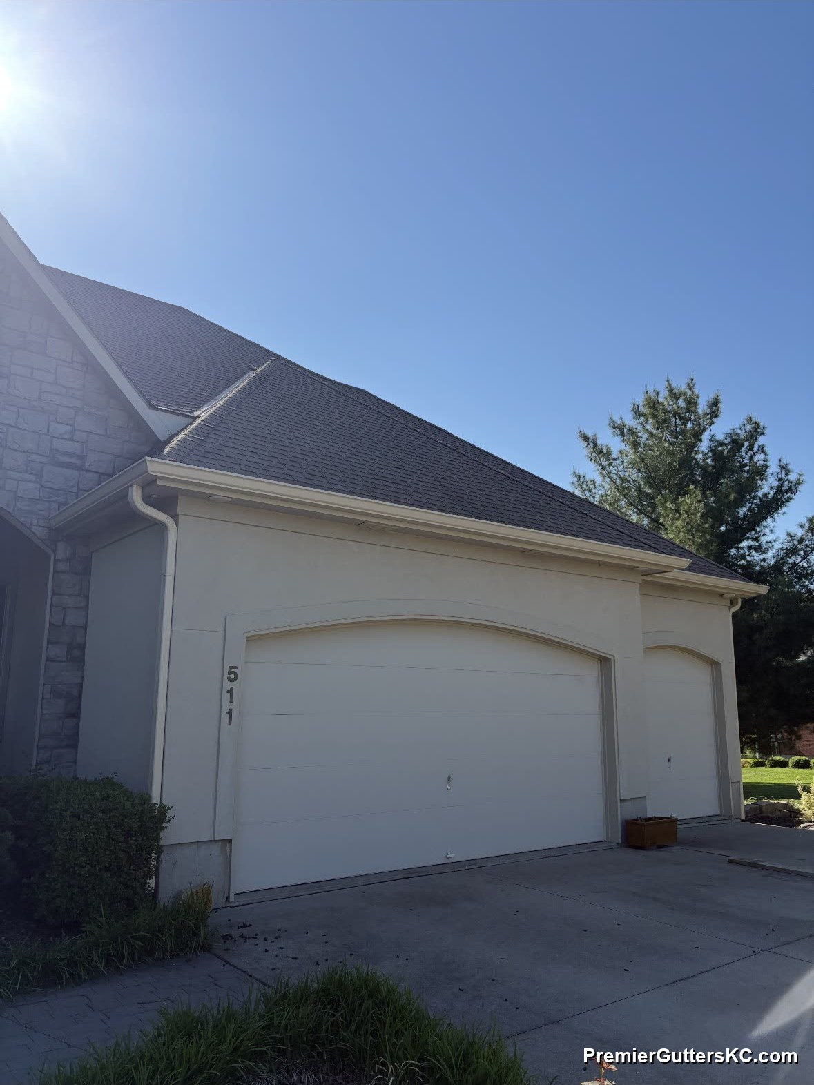 Cream color-matched seamless gutters on stucco home with stone accent in Kansas City
