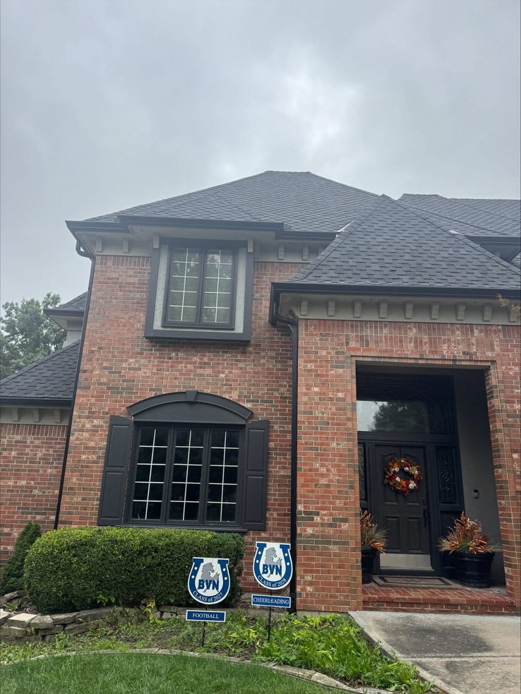 Black seamless gutters and downspouts on a brick two-story home in Overland Park, KS - Johnson County work by Premier Gutters KC