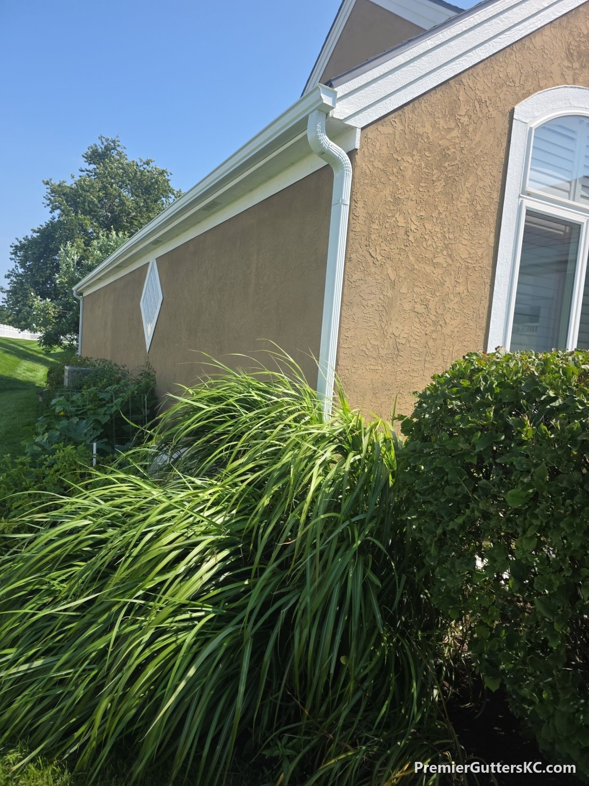 White seamless gutters along the side elevation of a stucco home in Overland Park, Kansas