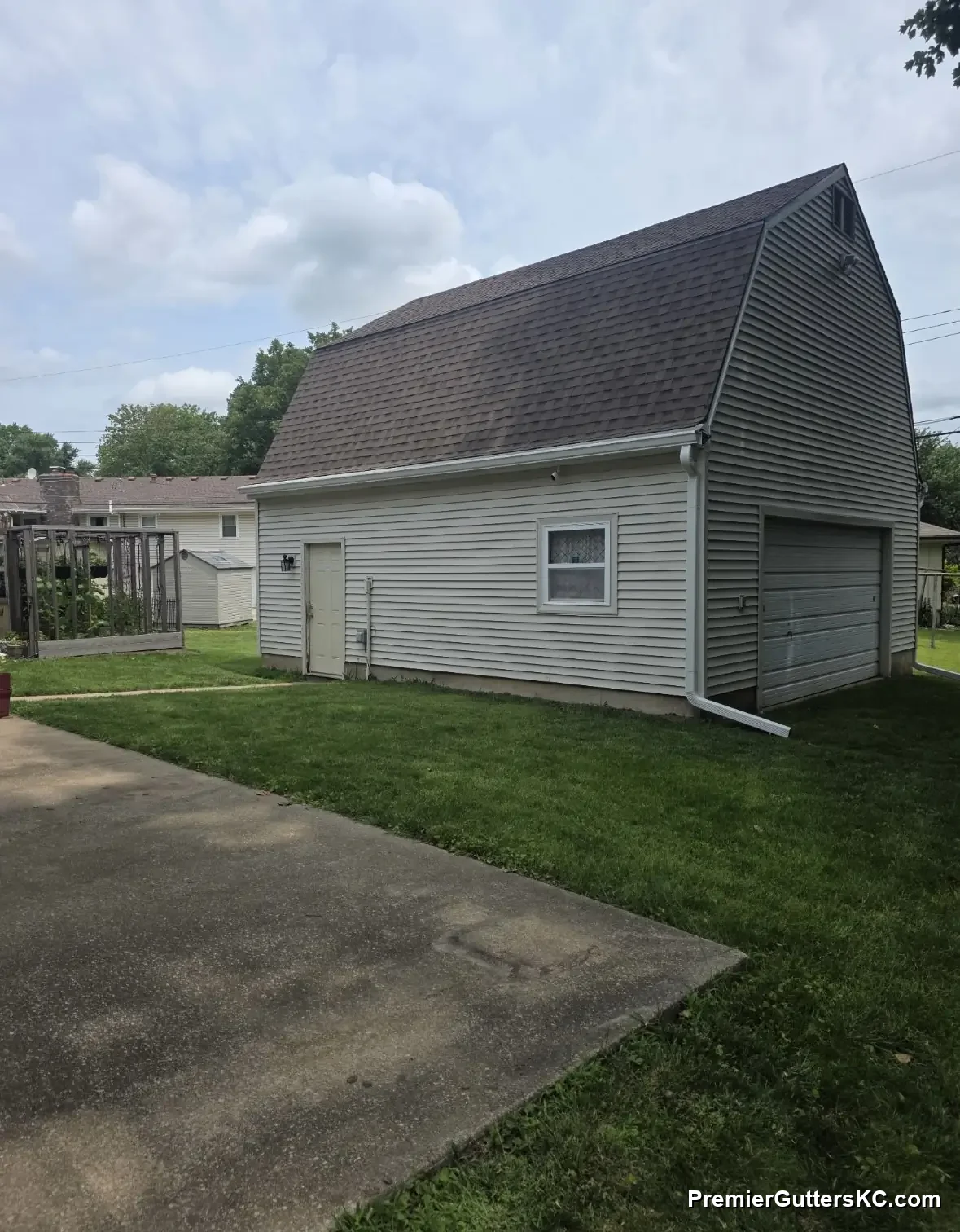 White seamless gutter and downspout draining to the driveway on a barn-style detached garage in Overland Park, KS, installed by Premier Gutters KC