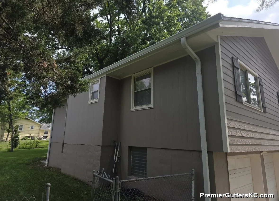 White seamless aluminum gutters and downspout on a split-level home on a wooded lot in Independence, MO, installed by Premier Gutters KC