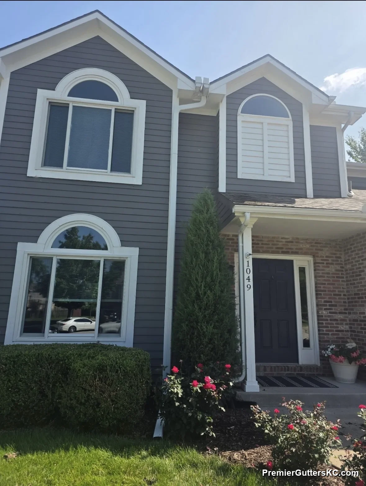 White seamless aluminum gutters and downspout on a two-story home with brick entry in Overland Park, KS, installed by Premier Gutters KC
