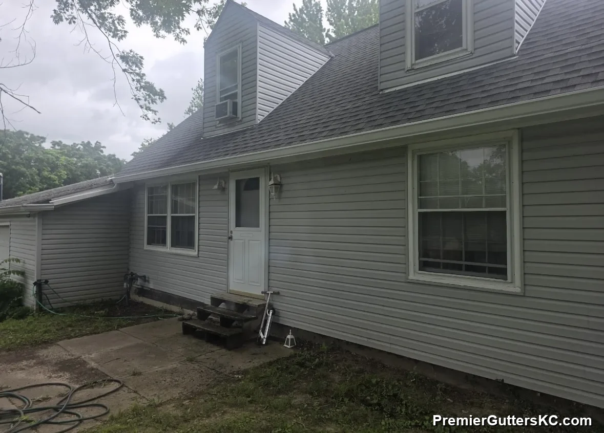 White seamless aluminum gutters along the eave of a gray cape-cod-style home in Overland Park, KS, installed by Premier Gutters KC